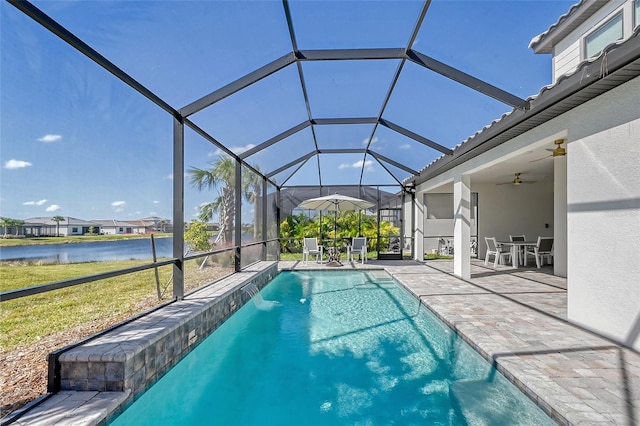 view of pool with a patio, pool water feature, ceiling fan, glass enclosure, and a water view