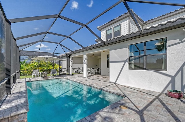 view of swimming pool featuring pool water feature, a patio area, ceiling fan, and glass enclosure