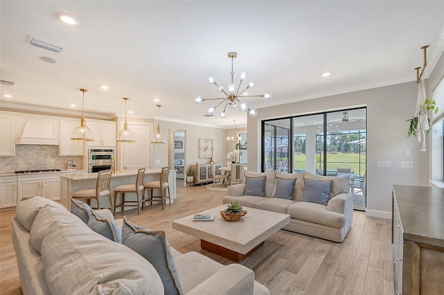 living room featuring ornamental molding, a notable chandelier, and light hardwood / wood-style floors