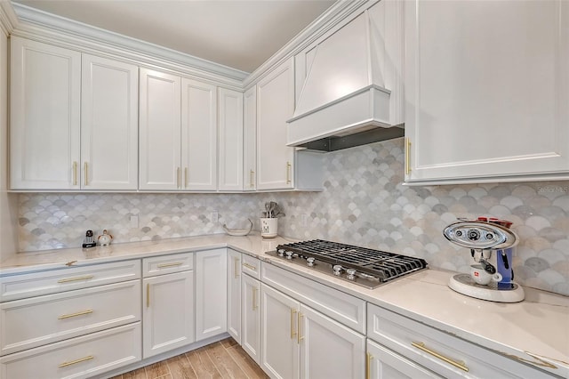 kitchen featuring premium range hood, light hardwood / wood-style floors, stainless steel gas cooktop, and white cabinets