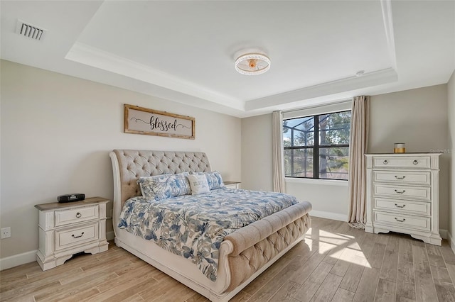 bedroom featuring a raised ceiling and light hardwood / wood-style flooring