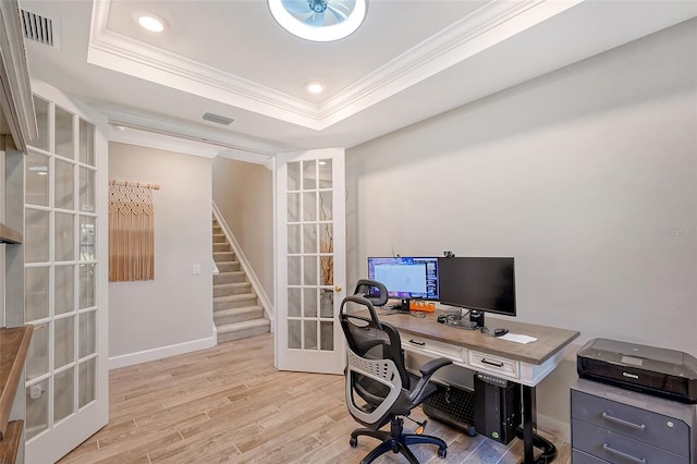 home office featuring crown molding, light hardwood / wood-style floors, french doors, and a raised ceiling