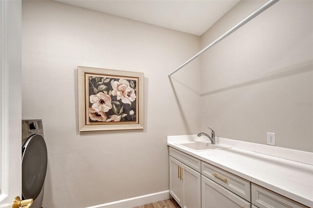 laundry area featuring cabinets, washer / clothes dryer, sink, and light hardwood / wood-style flooring