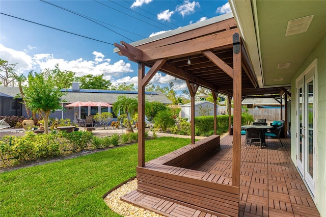 wooden deck featuring a storage shed, a lawn, and a patio