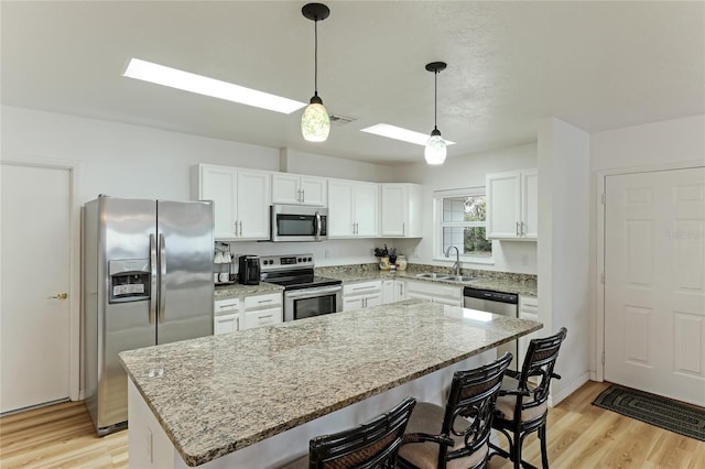 kitchen featuring stainless steel appliances, light stone countertops, sink, and a kitchen island