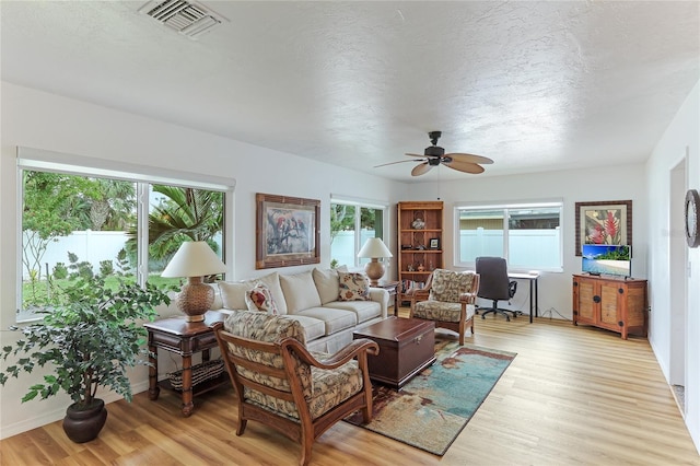 living room with plenty of natural light, light hardwood / wood-style floors, and ceiling fan