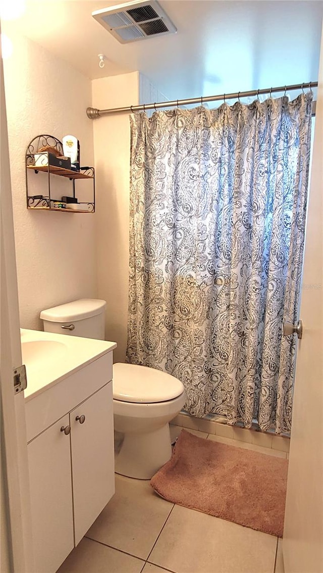 bathroom with toilet, vanity, and tile patterned flooring