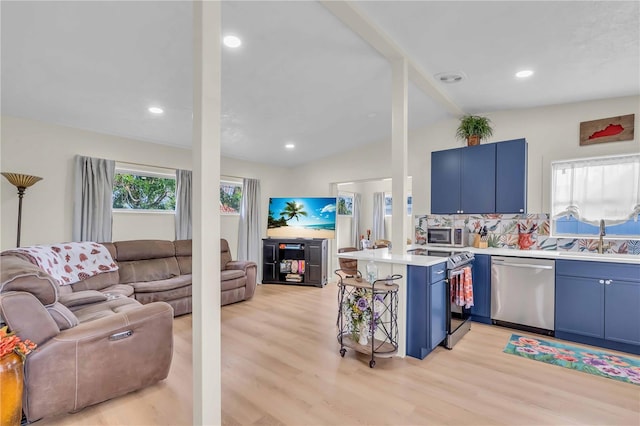 kitchen featuring appliances with stainless steel finishes, kitchen peninsula, lofted ceiling, blue cabinets, and light wood-type flooring