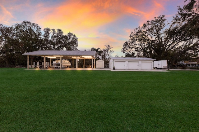 back of property featuring an outdoor structure, a yard, a garage, and metal roof