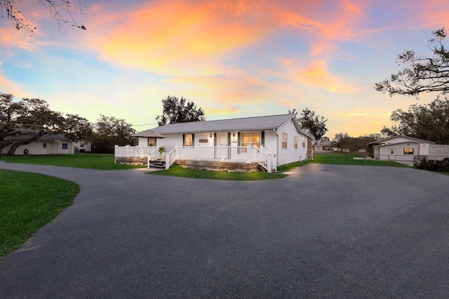 ranch-style home with a lawn and covered porch