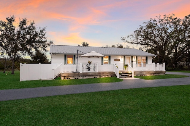 ranch-style house with metal roof, driveway, a porch, and a front yard