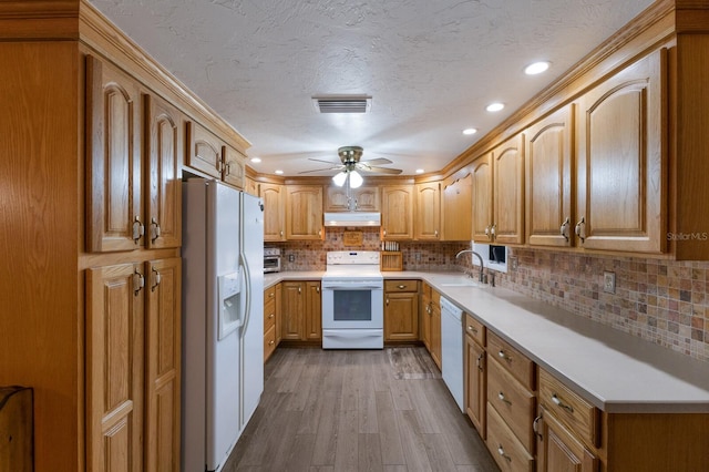 kitchen featuring visible vents, under cabinet range hood, a sink, dark wood finished floors, and white appliances