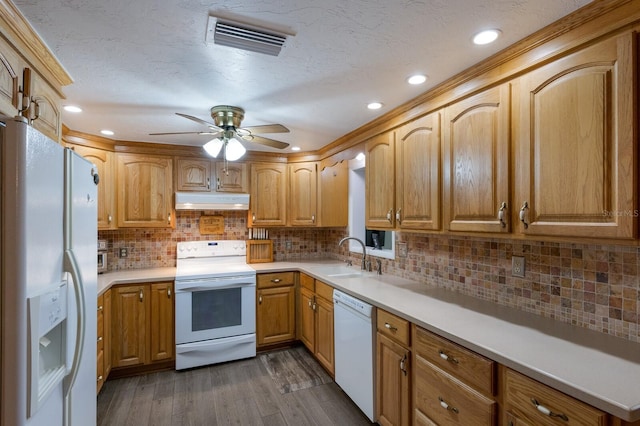 kitchen with white appliances, visible vents, dark wood-style flooring, a sink, and under cabinet range hood