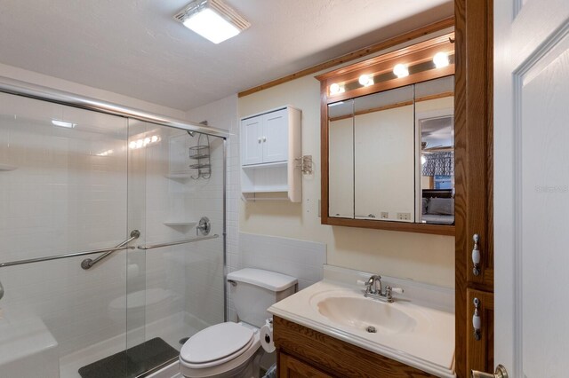 bathroom featuring toilet, vanity, a textured ceiling, and walk in shower