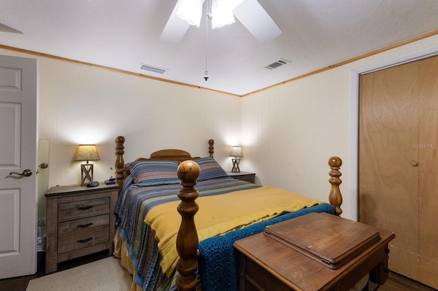 bedroom featuring hardwood / wood-style floors, a textured ceiling, ornamental molding, ceiling fan, and a closet