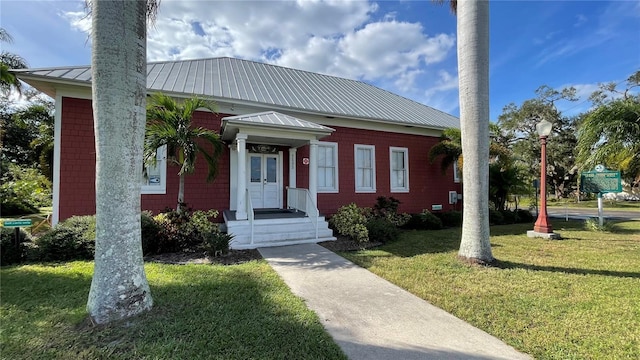 view of front of house featuring a standing seam roof, metal roof, and a front yard