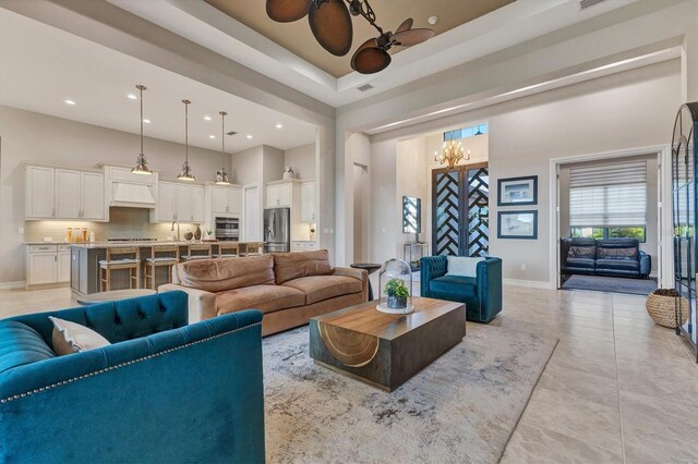 living room featuring ceiling fan with notable chandelier, light tile patterned floors, and sink