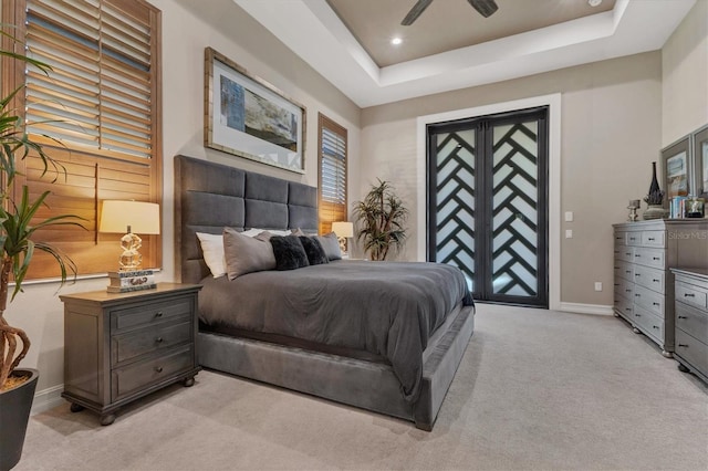 bedroom with access to outside, a tray ceiling, light colored carpet, and ceiling fan