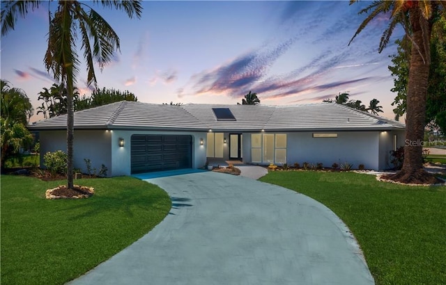 ranch-style house featuring a garage and a yard