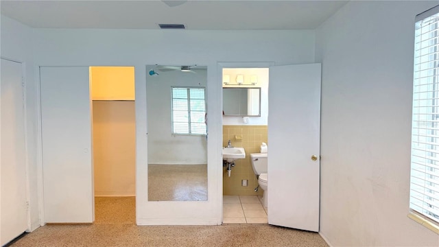 unfurnished bedroom with ensuite bath, tile walls, light tile patterned flooring, a closet, and a walk in closet