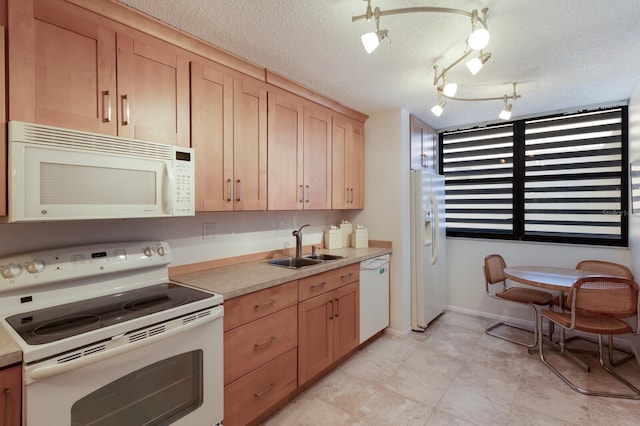 kitchen with sink, track lighting, light brown cabinets, a textured ceiling, and white appliances