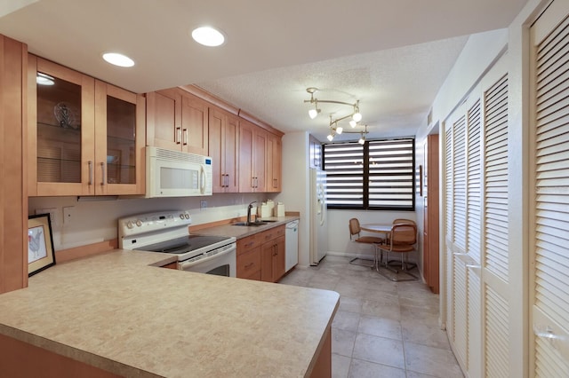 kitchen featuring sink, kitchen peninsula, a textured ceiling, an inviting chandelier, and white appliances