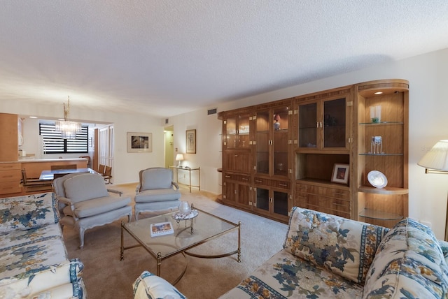 living room featuring a chandelier, a textured ceiling, and light carpet