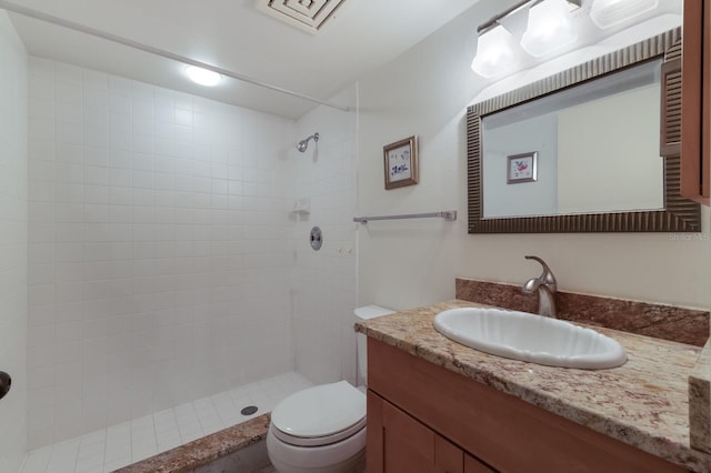 bathroom with toilet, vanity, and tiled shower