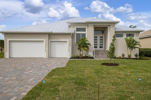 16381 Cape Horn Blvd, Punta Gorda, FL 33955 - prairie-style house featuring stucco siding, decorative driveway, metal roof, and a front yard
