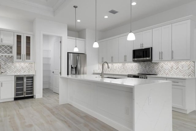 kitchen featuring white cabinets, stainless steel appliances, and beverage cooler