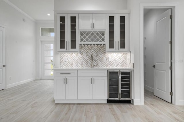 kitchen featuring beverage cooler, sink, crown molding, and light hardwood / wood-style flooring