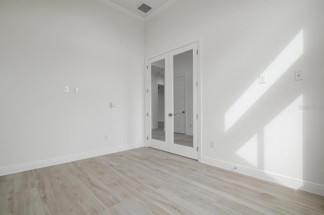 spare room with crown molding, french doors, and light wood-type flooring