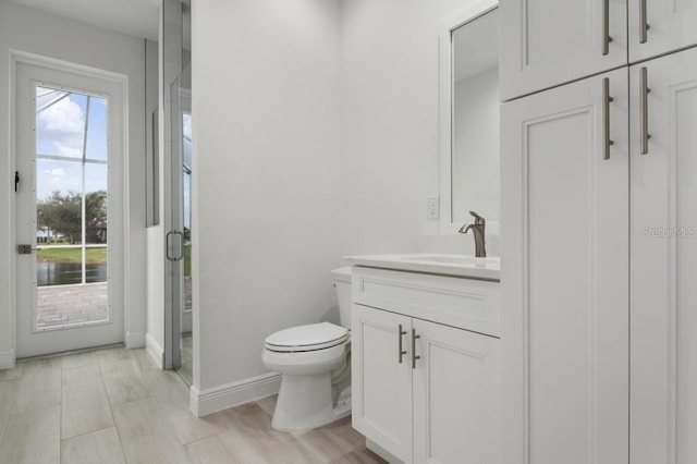 bathroom featuring toilet, an enclosed shower, and vanity