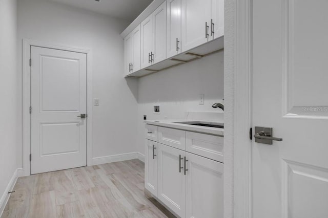 washroom with cabinets, washer hookup, electric dryer hookup, and light wood-type flooring