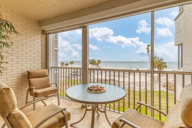 sunroom with a beach view and a water view