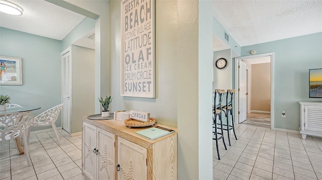 hallway featuring a textured ceiling and light tile patterned floors