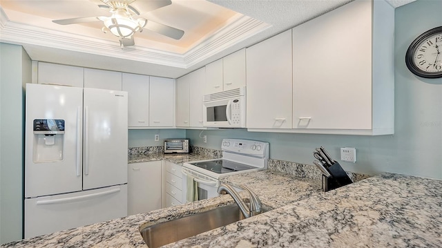 kitchen with white cabinets, sink, white appliances, and a tray ceiling