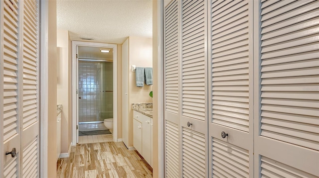 hallway with light hardwood / wood-style floors and a textured ceiling