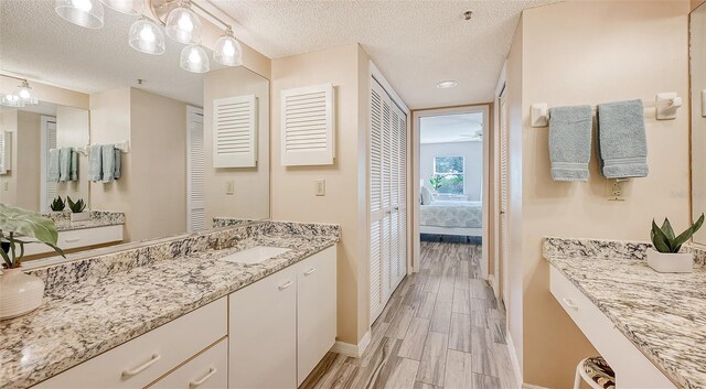 1328 Siesta Bayside Dr Unit 1328-C, Sarasota, FL 34242 - full bathroom featuring baseboards, connected bathroom, vanity, a textured ceiling, and wood finished floors