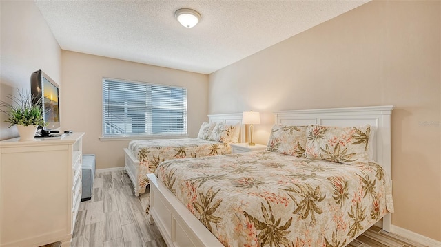 bedroom with light hardwood / wood-style flooring and a textured ceiling