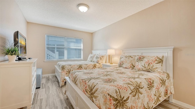 1328 Siesta Bayside Dr Unit 1328-C, Sarasota, FL 34242 - bedroom featuring light wood finished floors, a textured ceiling, and baseboards