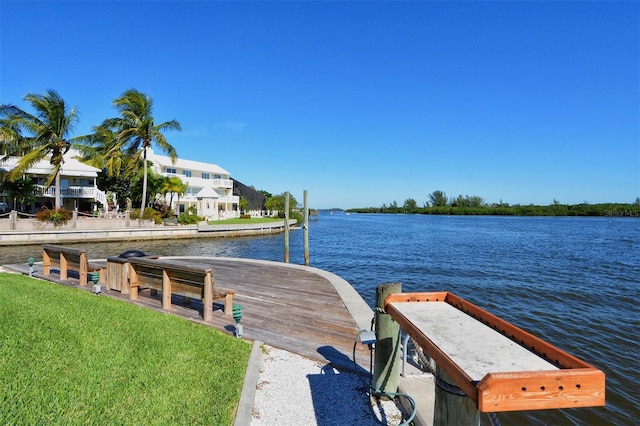 view of dock with a yard and a water view