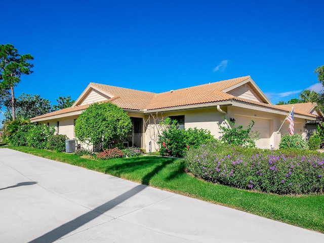 view of front of home with a front lawn, a garage, and central AC