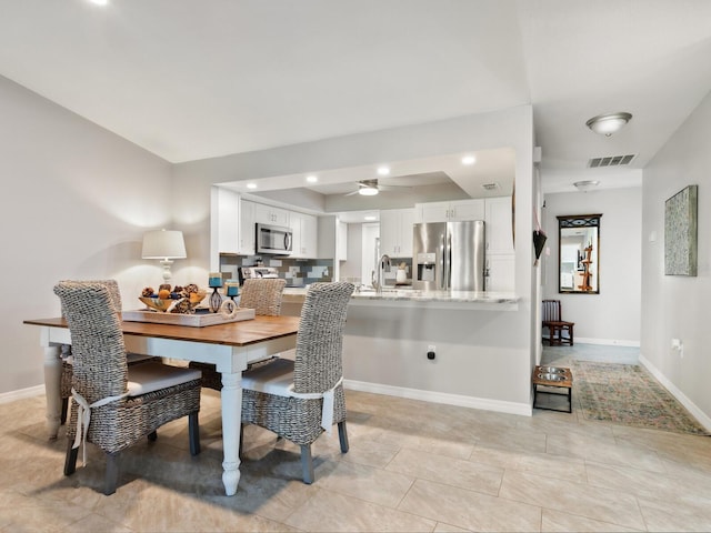 dining area featuring sink, light tile patterned floors, and ceiling fan