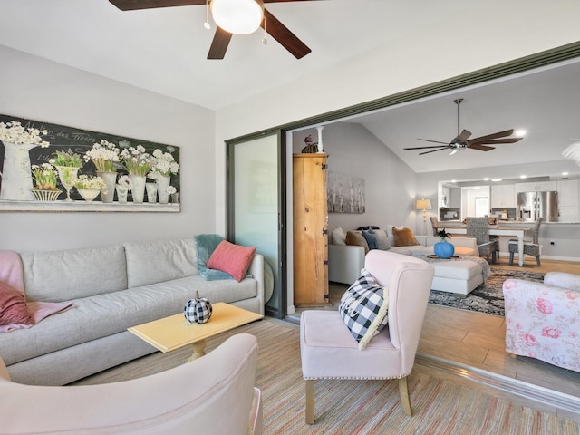 living room with ceiling fan, vaulted ceiling, and light hardwood / wood-style floors