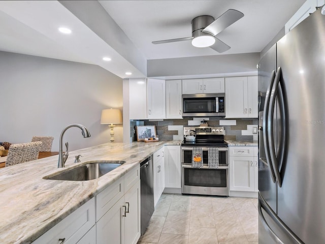 kitchen with stainless steel appliances, sink, light stone counters, white cabinets, and decorative backsplash