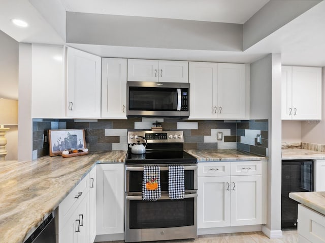 kitchen with stainless steel appliances, white cabinets, backsplash, and light stone counters