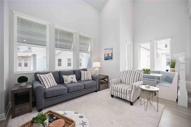 living room featuring a high ceiling, a healthy amount of sunlight, and light hardwood / wood-style flooring