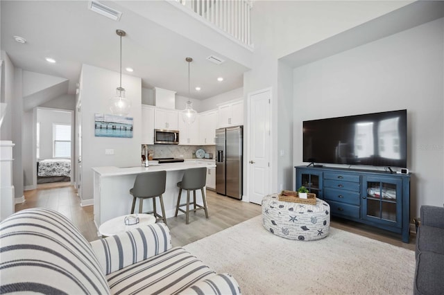 living room with light hardwood / wood-style floors and a towering ceiling