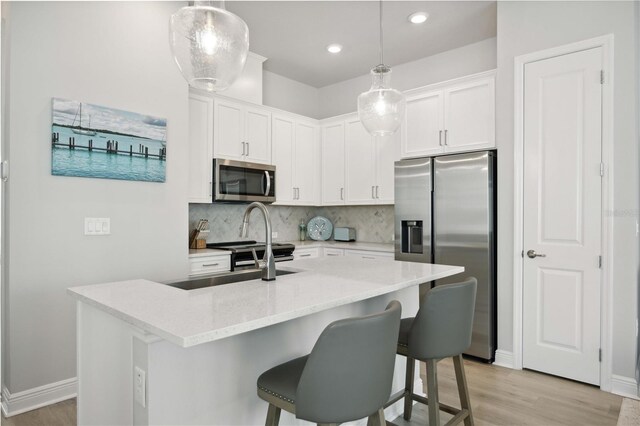 kitchen with white cabinetry, appliances with stainless steel finishes, and pendant lighting